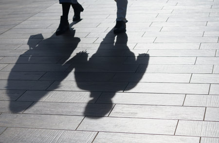 Shadow of a man and woman walking on the pavement in the city