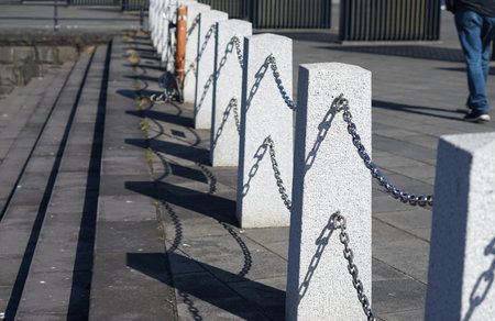 Row of white concrete fence with chain links on the promenade