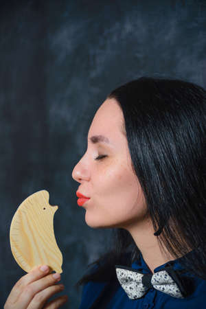 girl kisses wooden hedgehog on a background of black slate wallsの写真素材