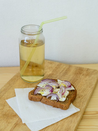 toast with onion feta oregano on a wooden cutting board with apple juice in the bankの写真素材