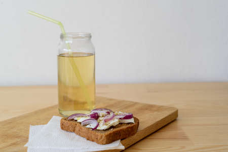toast with onion feta oregano on a wooden cutting board with apple juice in the bankの写真素材