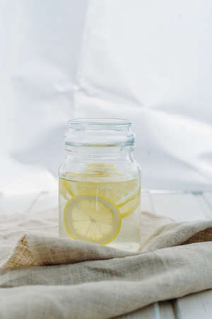 Lemonade with lemon slices in a jar at a white summer wooden backgroundの写真素材