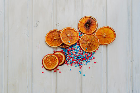slices of dried oranges and star sprinkles on a white background with copyspace