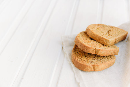 Slices of toast rye bread on napkin on white wooden boards with copyspace