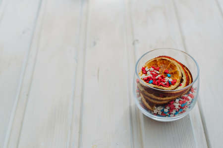 slices of dried oranges and star sprinkles in glass on a white background with copyspaceの写真素材