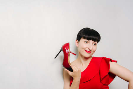 Beautiful young model woman in red dress posing over white backgroundの写真素材