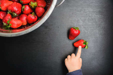 black desk background with copyspace, the child picks strawberriesの写真素材