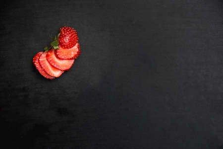a sliced strawberry on black wooden background top viewの写真素材