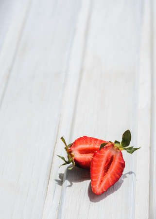 cut in half strawberry on white wooden background with copyspaceの写真素材