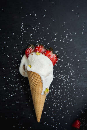 ice cream cone with strawberry and pistachio nuts sprinkled with coconutの写真素材