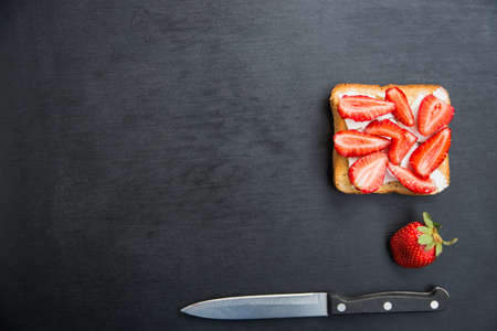 top view toast with feta and strawberries on black tableの写真素材