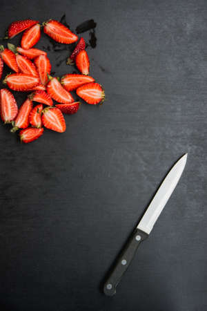 sliced strawberries and knife on black background with copyspaceの写真素材
