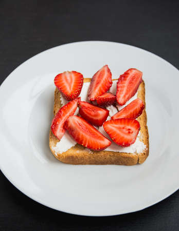 toast with feta and strawberries on black tableの写真素材