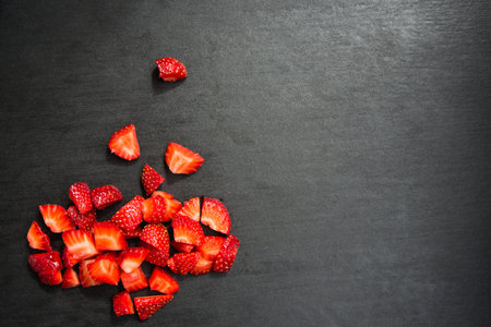 lobule sliced strawberries on black slate background