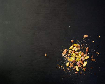 pile of pistachios on a black slate surface