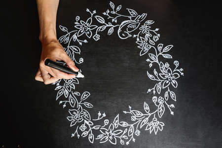 woman draws chalk marker autumn pattern on a black boardの写真素材