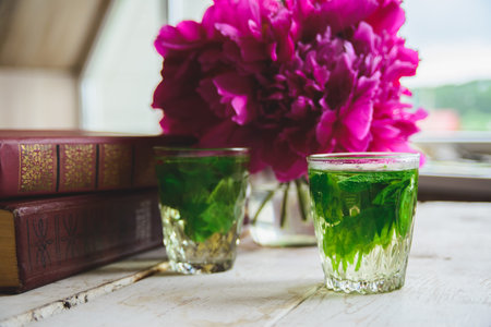 mint tea, peonies and books on white wooden deskの写真素材