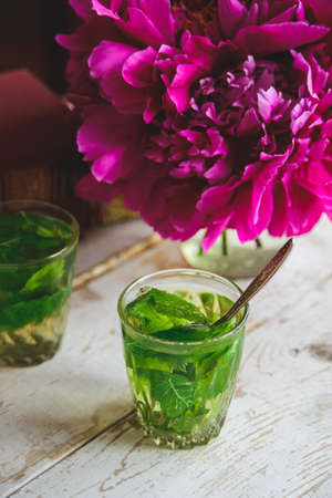 mint tea, peonies and books on white wooden deskの写真素材