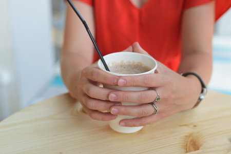young woman in red dress holding a drink at cafeの写真素材