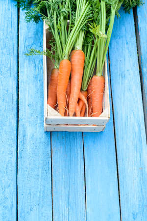 fresh carrots in wooden box on blue boardsの写真素材
