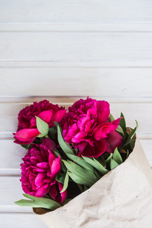 bouquet of peonies on white wooden background