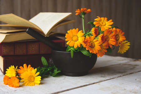 composition of calendula, books, cast-iron mortar on the tableの写真素材