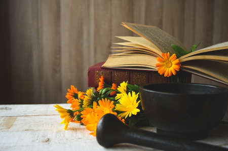 composition of calendula, books, cast-iron mortar on the tableの写真素材