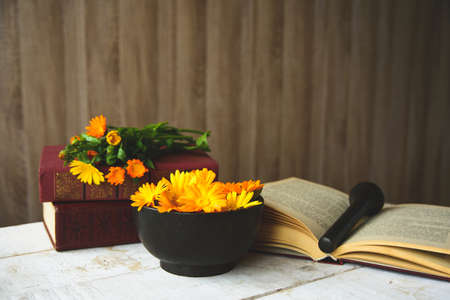 composition of calendula, books, cast-iron mortar on the tableの写真素材