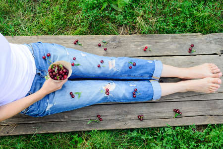 rustic harvester woman legs and fresh ripe cherriesの写真素材