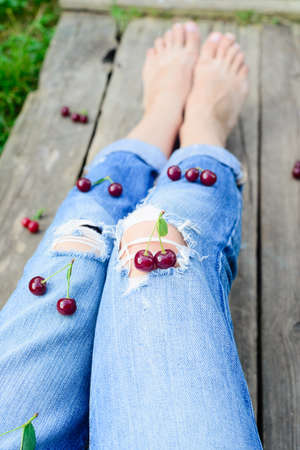 rustic harvester woman legs and fresh ripe cherriesの写真素材
