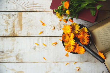 composition of calendula, books, cast-iron mortar on the tableの写真素材
