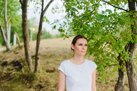 girl standing in park among the green trees