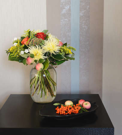 bouquet of apple, Chrysanthemum, rowan, stonecrop, anisetree, phlox near edible ingredients on plateの写真素材