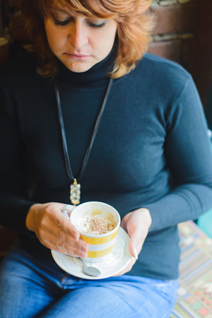redhead woman thinking while sitting in a cafe