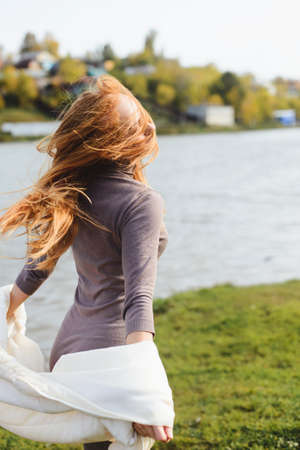 redhead young woman posing in the autumn park near waterの写真素材