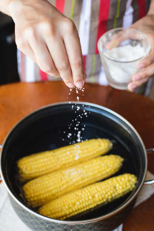 golden corn in black bowl on brown tableの写真素材