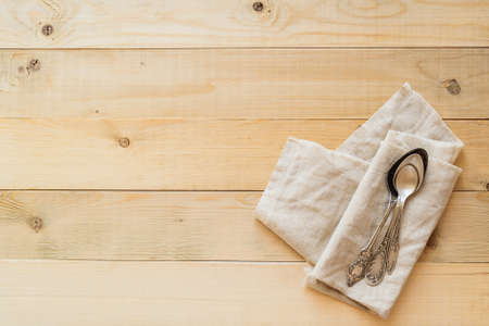top view of three vintage spoons on a linen fabric on wooden boards background with copy negative spaceの写真素材