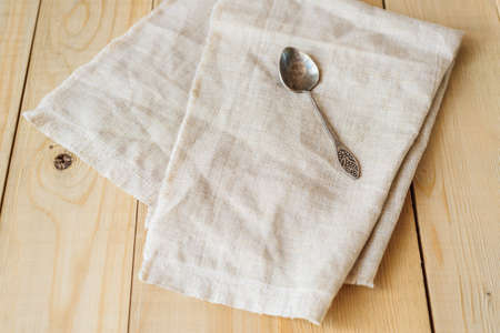 view from angle above of one vintage spoon on a linen fabric on wooden boards background with copy negative spaceの写真素材