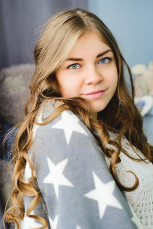 Portrait of happy smiling young blond caucasian woman with american flag wrapped around her