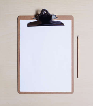 top view flat lay of blank white paper sheet , clipboard, pencil on wooden table with copy spaceの写真素材