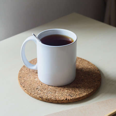 White cup of black tea and cork coaster on wooden table
の写真素材