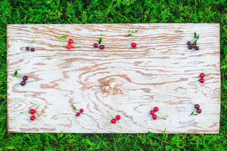 top view flat lay of fresh ripe red cherries frame on a white rustic wood board background with copy space for textの写真素材