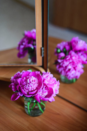 close-up pink peonies in glass jar on table with mirror reflection, congratulations for everyday conceptの写真素材