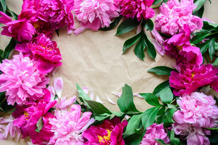 Top view of close-up frame of pink and red cut peonies on kraft paper background with copy space for textの写真素材