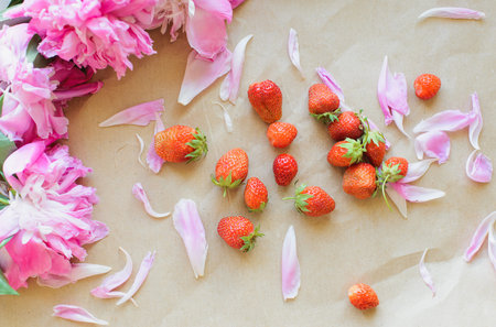 Top view of peonies and strawberries lie on a table on kraft paper photo in natural lightの写真素材