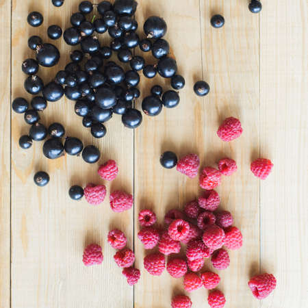 top view of red raspberries and black currant on wooden table as ingredient to healthy cocktail, beverage, yogurt, smoothieの写真素材
