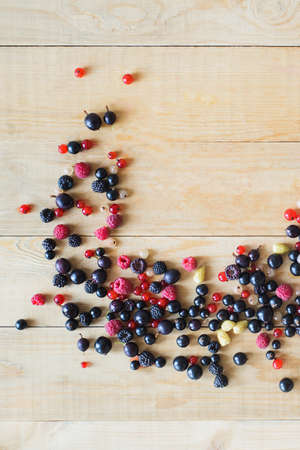 Red, white, black currant, red and black raspberries, white strawberries on wooden table as ingredient to healthy eating and drinkingの写真素材