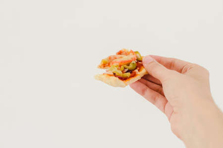 Hand of a white caucasian woman holding a slice of pizza on a white backgroundの写真素材