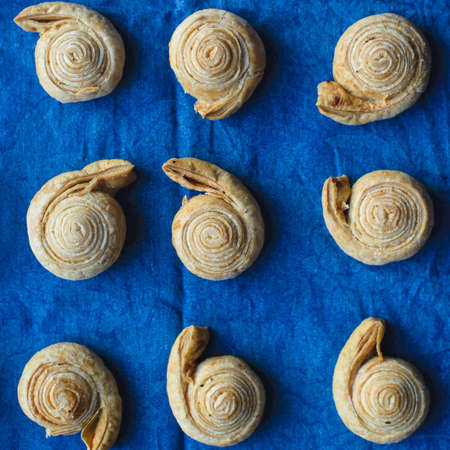 top view of fresh baked homemade sweet puff pastry bagel roll as spiral with sugar and cinnamon on blue jeans cloth backgroundの写真素材