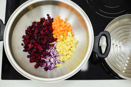 diced ingredients for vegetarian soup in a saucepan on electric stoveの写真素材